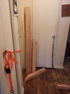 an open door in a room with wooden flooring and tools on the ground next to it