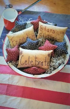 a bowl filled with pillows on top of a flag table cloth and two mugs