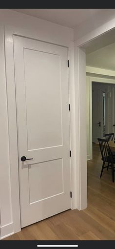 an open door leading to a dining room with chairs and table in the background on a hard wood floor