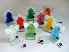 a group of glass angel figurines sitting on top of a white table next to each other