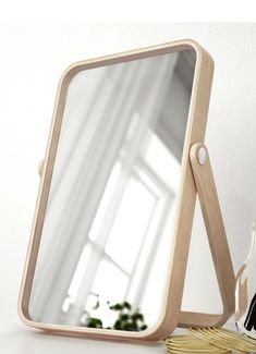 a mirror sitting on top of a white table next to a vase and plant in front of it