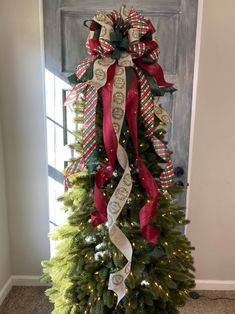 a decorated christmas tree with ribbons on it in front of a door that says merry