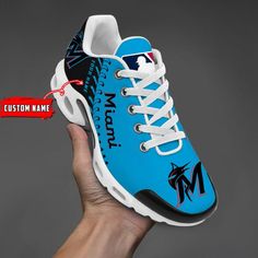 a hand holding up a blue and white shoe with the name custom printed on it