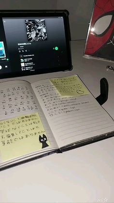 an open notebook sitting on top of a desk next to a computer monitor and keyboard