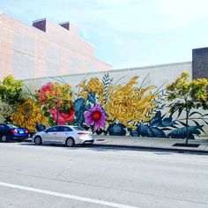 two cars parked in front of a large mural on the side of a building