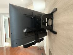 a flat screen tv mounted to the side of a wall in a room with hard wood flooring