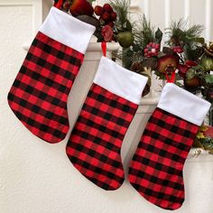 two christmas stockings hanging from the side of a window sill next to a potted plant