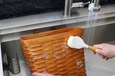 a person is using a brush to clean a basket under a sink faucet