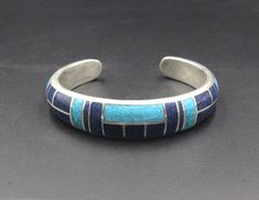 This is a heavy duty sterling silver cuff bracelet made with inlaid natural turquoise and natural lapis lazuli stone. The width is 12mm, tapering to 8mm. The thickness is 6 mm. The gap is 1.25 inches for a man's wrist size; 1 inch for a woman's wrist size. Select your wrist size from the drop down menu, and we will make your bracelet to fit. Please measure your wrist size if you are unsure of the size. Solid sterling silver and stone inlay bracelets cannot be changed. No returns are accepted unl Artisan Blue Cuff Bangle Bracelet, Artisan Blue Bangle Cuff Bracelet, Southwestern Sterling Silver Cuff Bracelet In Blue, Blue Polished Bangle Cuff Bracelet, Adjustable Blue Engraved Cuff Bracelet, Southwestern Engraved Blue Cuff Bracelet, Blue Sterling Silver Engraved Bracelet, Blue Engraved Sterling Silver Bracelets, Adjustable Blue Cuff Bracelet With Inlay