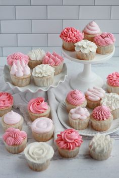 cupcakes are arranged on three tiered trays with pink and white frosting