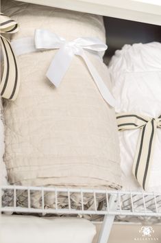 two white pillows with bows on them sit in a shelf next to some other items