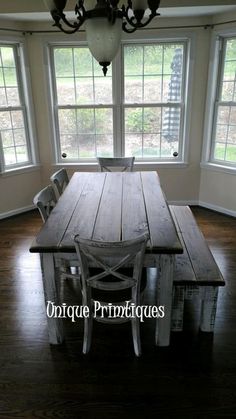 a dining room table and chairs in front of two large windows with chandelier