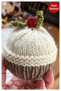 a knitted cupcake with a red flower on top is shown in the foreground