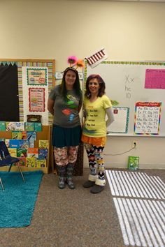 two women standing next to each other in front of a bulletin board