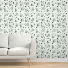 a white couch sitting in front of a wall with grey and white elephants on it