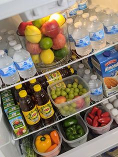 an open refrigerator filled with lots of different types of fruits and vegetables next to bottled water