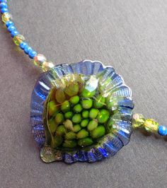 "The lovely glass pendant was made by Christian Luginger, a local, award winning glass-blower. I chose green Swarovski beads and lapis to complement the colors in the pendant.  The cones and clasp are sterling silver. The necklace is 10\" long.  This is a one of a kind necklace." Green Beaded Necklaces With Recycled Glass For Gifts, Green Recycled Glass Beaded Necklace As Gift, Green Recycled Glass Beaded Necklaces For Gifts, Green Recycled Glass Beaded Necklace Gift, Green Beaded Jewelry With Recycled Glass, Green Beaded Jewelry From Recycled Glass, Blue-green Round Beads Jewelry Gift, Green Beaded Jewelry In Recycled Glass, Artisan Green Beaded Necklace With Czech Glass