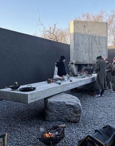 some people are standing around a table with food on it and one person is cooking