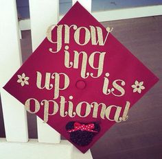 a graduation cap that says grow ing up is optimal on the side of a white fence