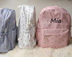 three personalized backpacks sitting next to each other on a white furnishing