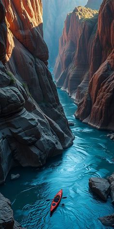 a red kayak floating through a canyon filled with rocks