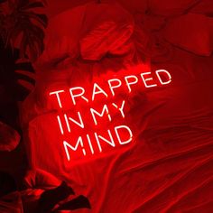 a neon sign that reads trapped in my mind on a bed with pillows and blankets