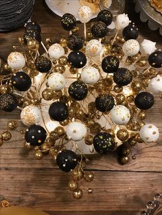 an assortment of black and white ornaments on a wooden table with plates in the background