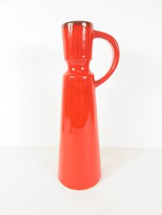 a red vase sitting on top of a white table