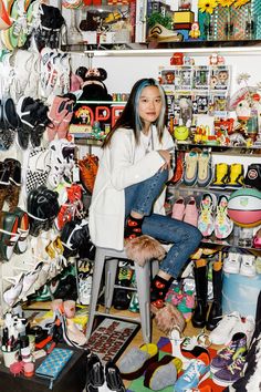 a woman is sitting on a stool surrounded by shoes and other items in a store