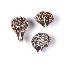 three wooden brooches with designs on them, one has a tree in the middle