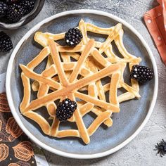 a plate with waffles and blackberries on it next to some other items