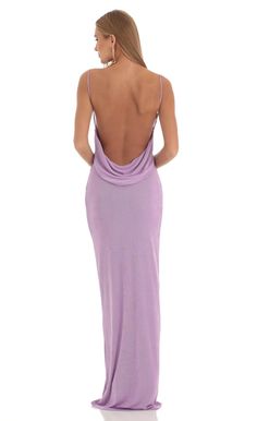 a woman in a long purple dress is looking back at the camera and she has her hands on her hips