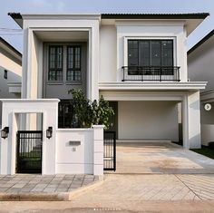 a white two story house with black iron gated entry way and windows on the second floor