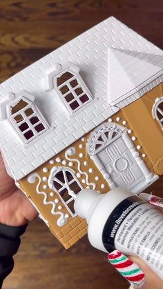 someone is painting a gingerbread house with white and brown paint on the front door