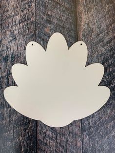 a white paper cut out of the shape of a flower on a wooden background with clippings