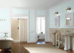 a bathroom with blue and white walls, wood floors and a claw foot bathtub