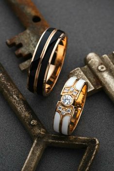 two wedding rings sitting next to each other on top of a key and keys in front of them