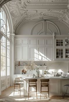 a large kitchen with white cabinets and an arched doorway leading to the dining room area