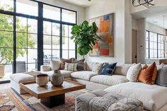 a living room filled with lots of furniture and large windowed windows in the background