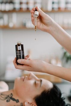 a woman is getting her hair done by a beauper in a beauty salon and she is holding a bottle of oil