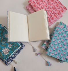 an open book sitting on top of a table next to several different colored fabric pieces