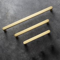 three wooden handles are shown on a gray surface, one is yellow and the other is black