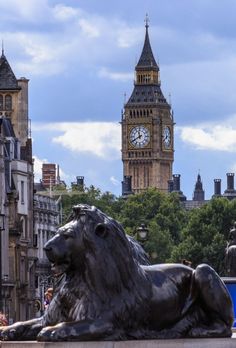 a lion statue in front of the big ben clock tower