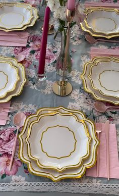 the table is set with pink and gold plates