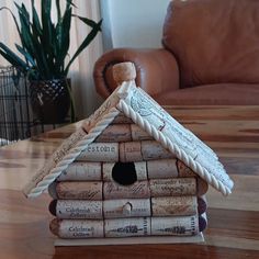 a birdhouse made out of wine corks sitting on a table next to a couch