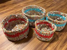 four baskets with sprinkles on them sitting on a wooden floor next to each other