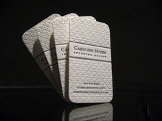 three white business cards sitting next to each other on top of a black countertop