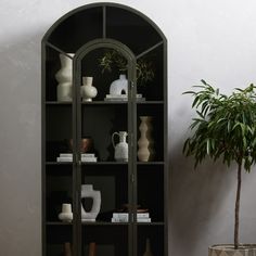 a black bookcase with shelves and vases on it