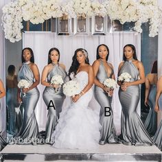 a group of women standing next to each other in front of a white flower arch