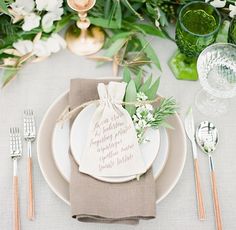 a table setting with place settings and flowers on it, including napkins, silverware